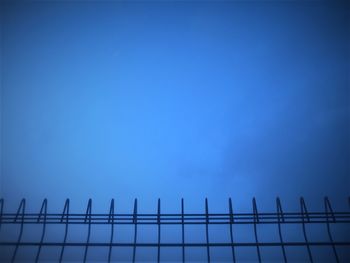 Low angle view of fence against clear blue sky