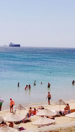 People on beach against clear sky