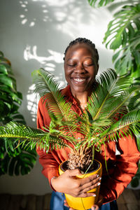 Portrait of young woman holding plant