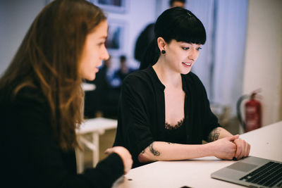 Woman looking at camera while sitting on table