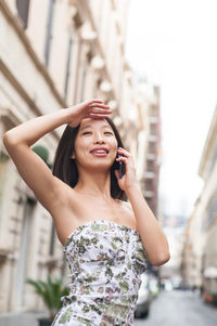 Young woman using phone while standing on street