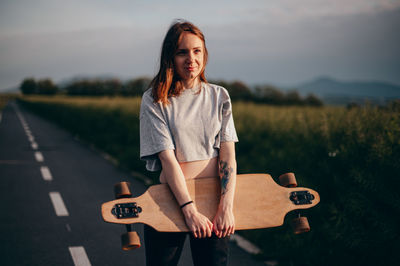 Young woman standing with skateboard