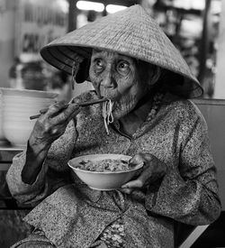 Senior woman eating noodles at home
