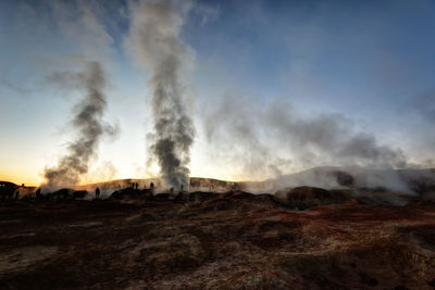 Smoke emitting from land against sky