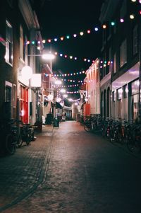 Illuminated street amidst buildings at night