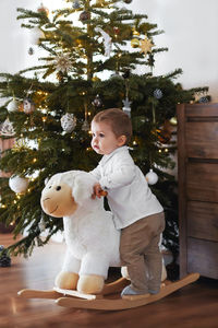 Boy rides a sheep near the christmas tree