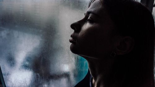 Side view of depressed woman against window