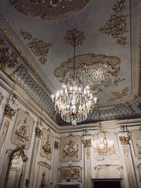 Low angle view of illuminated chandelier hanging on ceiling in building