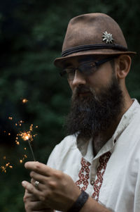 Young man burning sparklers while standing outdoors