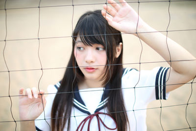 Young woman standing by sports net