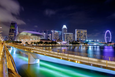 Footbridge over river in illuminated city at night