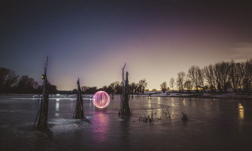 Reflection of trees in lake at night