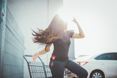 Back lit woman dancing by shopping cart