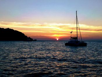 Silhouette sailboat sailing on sea against sky during sunset