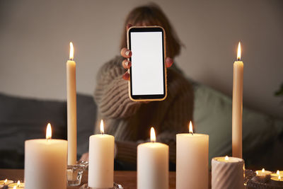 Woman showing phone over lit candles