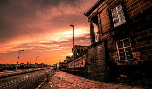 Street amidst buildings against sky during sunset