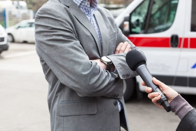 Cropped hand of female reporter interviewing man on street
