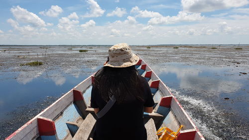 Rear view of woman standing by sea against sky