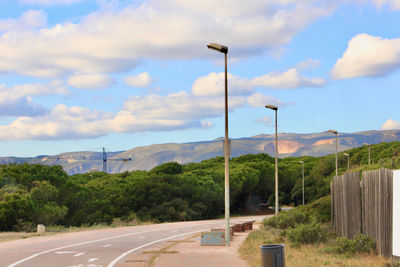 Street leading towards mountains against sky