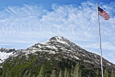 American flag by mountain against sky during winter