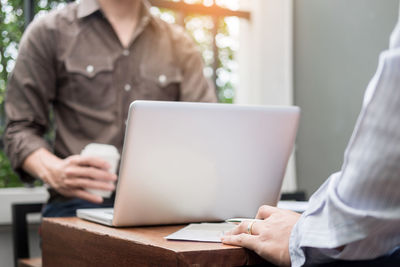 Midsection of woman using mobile phone while sitting on table