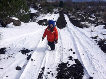 High angle view of child walking on snow covered field