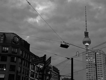 Low angle view of communications tower against cloudy sky