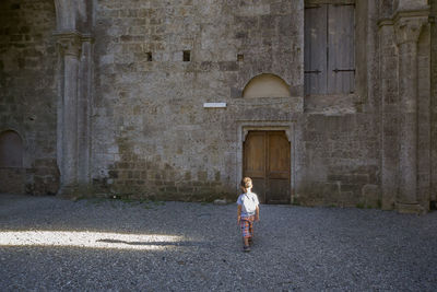 Rear view of boy walking on street by old building