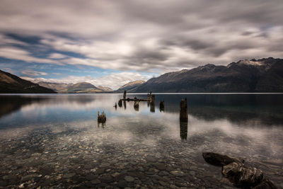 View of wooden post in lake with mountains in background