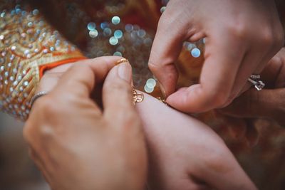Close-up of mother wearing a jewellery on bride during wedding day