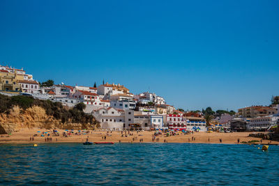 Townscape by sea against clear blue sky