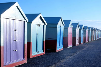 Beach huts against buildings against blue sky