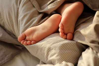 Children's legs stick out from under the warm blanket. concept of care, proper sleep, home comfort