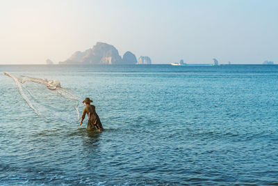 Man fishing in sea against clear sky