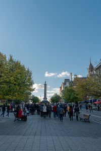 People on street in city against sky