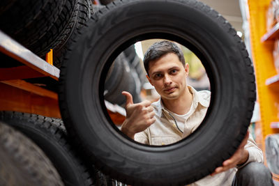 Portrait of man holding tire at store