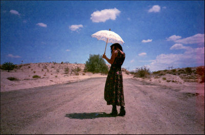 Woman with umbrella standing on road