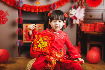 Portrait of cute girl wearing costume holding box at home