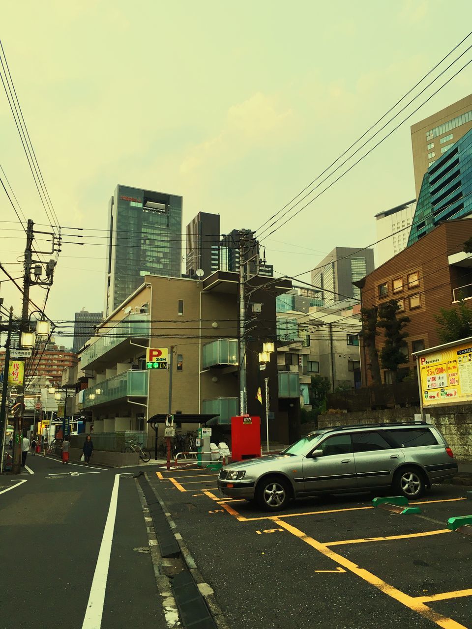 transportation, land vehicle, mode of transport, architecture, built structure, road, city, road marking, city street, sky, the way forward, city life, outdoors, diminishing perspective, day, stationary, parking, no people, parked, vanishing point