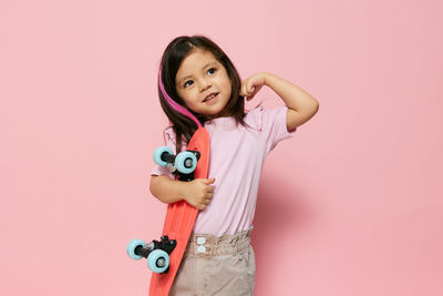 Portrait of cute girl with toy against pink background