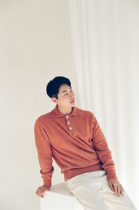 Portrait of young man sitting on chair at home