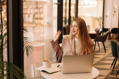 Portrait of a young business woman in glasses and business clothes looking at the camera in a cafe