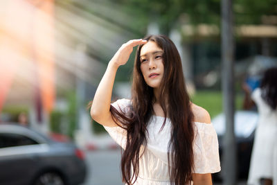 Young woman shielding eyes while standing on road