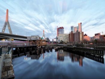 Bridge over river by buildings against sky in city