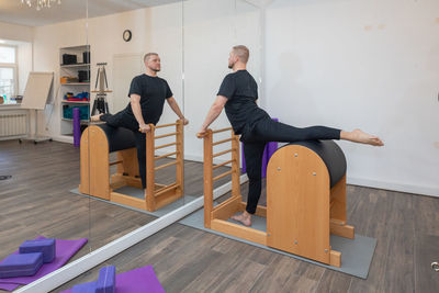 Male fitness pilates trainer shows exercises on special simulators. pilates stretch tables