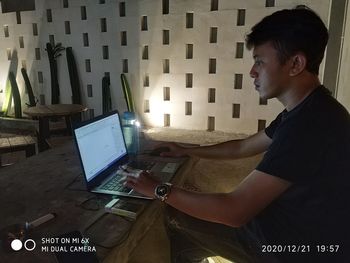 Side view of young man using laptop