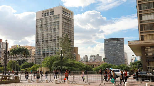 People on buildings in city against sky