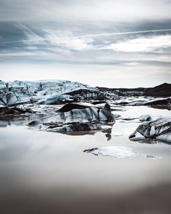 Icebergs melting in lake against sky