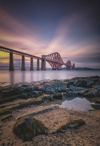 Bridge over sea against sky during sunset