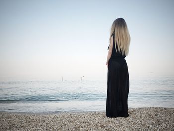 Rear view of full length woman standing on beach
